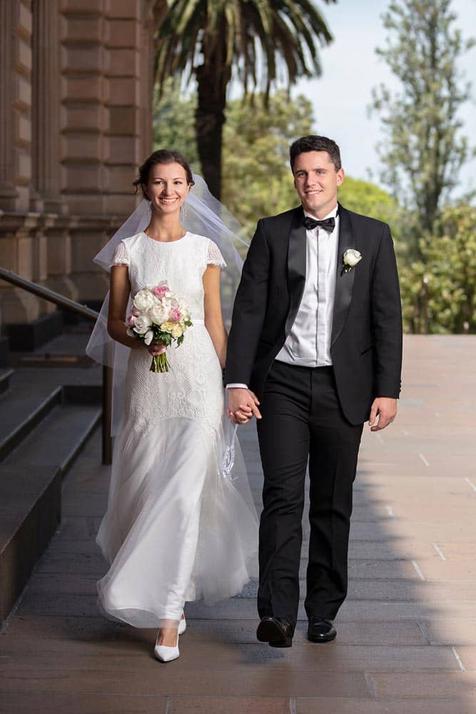Bride and groom walking and holding hand at old treasury building